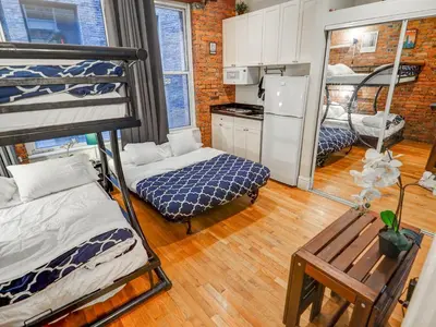 a room with two bunk beds and a kitchen at Metropolitan Studio Apartments Manhattan in New York
