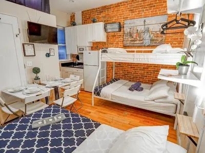 a room with two bunk beds and a kitchen at Metropolitan Studio Apartments Manhattan in New York