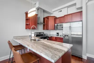 a kitchen with wooden cabinets and a granite counter top at Palatial 1BR with Rooftop Pool in Philadelphia