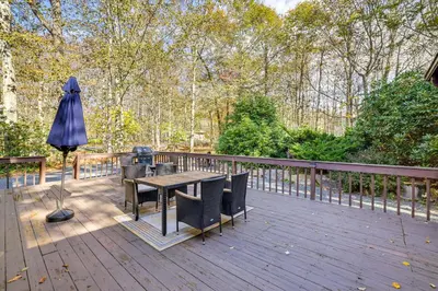 a wooden deck with a table and an umbrella at Near Water Parks Pet-Friendly Tobyhanna Getaway! in Tobyhanna