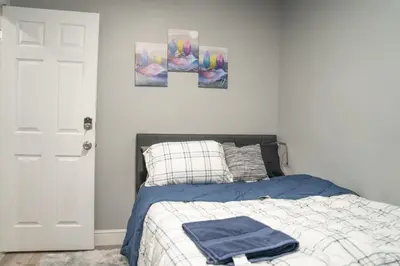 a bedroom with a bed with three paintings on the wall at Divine Villa and Resort -26 Grace Street Irvington NJ -EWR airport -Prudential - NJIT -Penn station in Irvington
