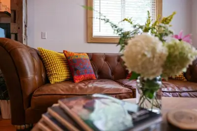 a living room with a brown leather couch with colorful pillows at Poconos Cabin Year Round Bliss in Greentown