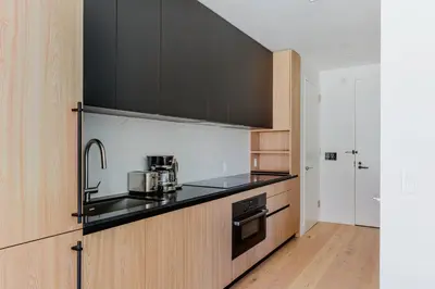 a kitchen with black counter tops and wooden cabinets at Blueground Midtown West gym doorman wd NYC-1560 in New York
