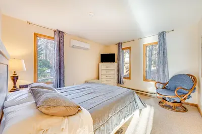 a bedroom with a bed and a chair and windows at Lakefront Cabin Kayaks, Paddle Boards and Fishing in Pocono Lake