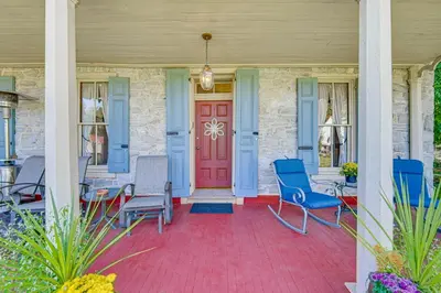 a porch with blue chairs and a red door at Walk to Creek Mount Joy Home with Peacocks On-Site! in Mount Joy