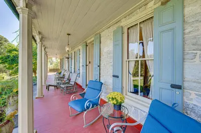a porch with blue chairs and tables and windows at Walk to Creek Mount Joy Home with Peacocks On-Site! in Mount Joy