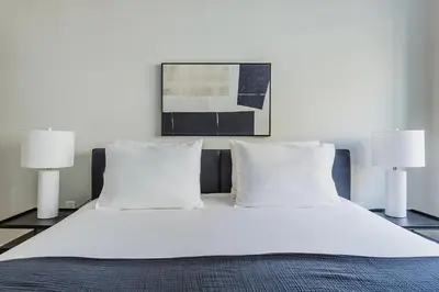 a bed with white sheets and pillows and two lamps at Blueground Jersey City 1bd apartment NYC-1603 in New York