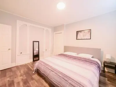 a white bedroom with a large bed and a mirror at Serene Two-Bedroom Retreat - close to NYC in Jersey City