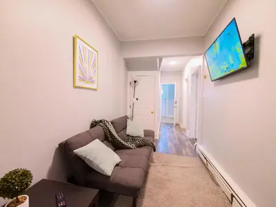 a living room with a couch and a tv on a wall at Serene Two-Bedroom Retreat - close to NYC in Jersey City