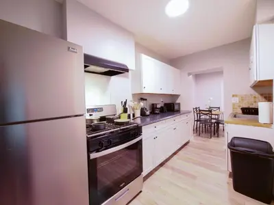 a kitchen with white cabinets and a stainless steel refrigerator at Modern comfort-2BR haven mins to NYC in Jersey City