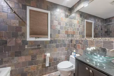 a bathroom with a toilet and a glass sink at The Orange Oasis in Bayonne