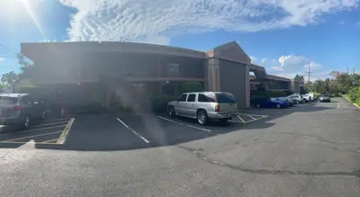 a parking lot with cars parked in front of a building at Travelers Inn in South Brunswick Terrace
