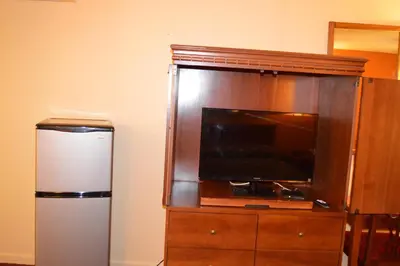 a large entertainment center with a tv and a refrigerator at Travelers Inn in South Brunswick Terrace