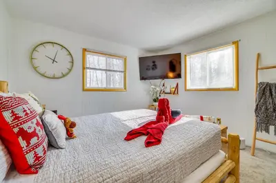 a bedroom with a bed and a clock on the wall at Private Hot Tub and Game Room Pocono Family Cabin! in Tobyhanna