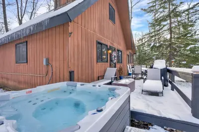 a hot tub on the patio of a house at Private Hot Tub and Game Room Pocono Family Cabin! in Tobyhanna
