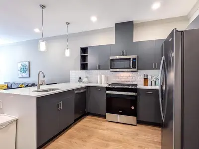 a kitchen with gray cabinets and a stainless steel refrigerator at 221 Modern 1BR Apt Walk to NJT in Dunellen