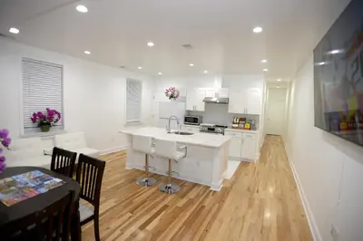 a kitchen with white cabinets and a table and a dining room at Spacious and Brand New Apartment in Point Breeze - Prime Location in Philadelphia