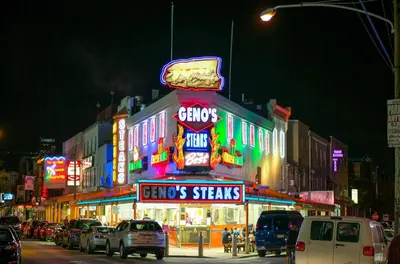 a street with cars parked in front of a building with neon signs at Spacious and Brand New Apartment in Point Breeze - Prime Location in Philadelphia