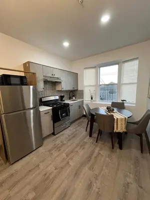 a kitchen with a stainless steel refrigerator and a table at Apartment Few Minutes NYC and Prudential Center in Newark