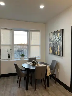 a dining room with a table and chairs and two windows at Apartment Few Minutes NYC and Prudential Center in Newark