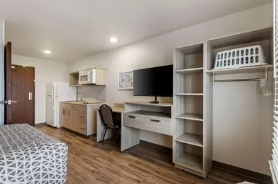 a small room with a bed and a desk with a television at WoodSpring Suites Easton Nazareth in Easton