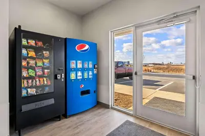 a pepsi machine next to a sliding glass door at WoodSpring Suites Easton Nazareth in Easton