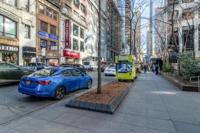 a blue car parked next to a tree on a city street at Blueground Midtown gym wd ac nr Rock Ctr NYC-1536 in New York