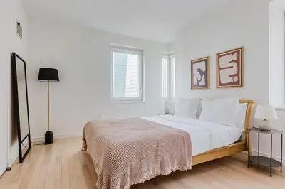 a white bedroom with a large bed with white pillows at Blueground Midtown gym wd ac nr Rock Ctr NYC-1536 in New York