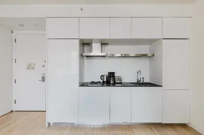 a white kitchen with white cabinets and a sink at Blueground Midtown gym wd ac nr Rock Ctr NYC-1536 in New York