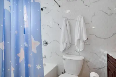 a bathroom with a toilet and a blue shower curtain at 3BD Stevens Universe Theme - Games - Backyard in Tobyhanna