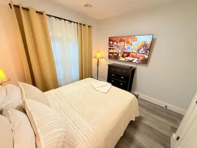 a bedroom with a bed and a flat screen tv at The Luxury Suite - 1BR with Gym & Office in Paterson