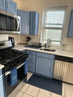 a kitchen with blue cabinets and a stove and a sink at Genevieves lovely suite in Jersey City