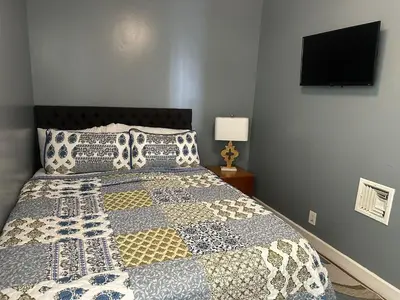 a bedroom with a bed and a tv on the wall at Genevieves lovely suite in Jersey City