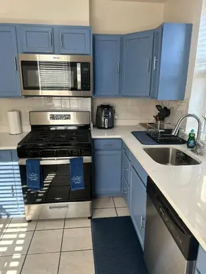 a kitchen with blue cabinets and a stove and a sink at Genevieves lovely suite in Jersey City