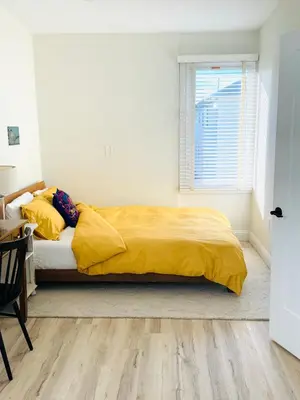a bedroom with a bed with yellow sheets and a window at Designer cozy 1 private bedroom w full bath & yard 20 min to nyc in Harrison