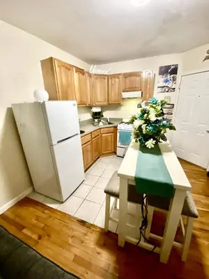 a kitchen with a refrigerator and a table with flowers on it at Apart Studio West NYNJ 12Mints From NYCity TimeSquare in West New York