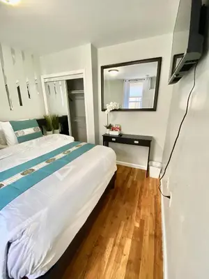a bedroom with a large white bed and a mirror at Apart Studio West NYNJ 12Mints From NYCity TimeSquare in West New York