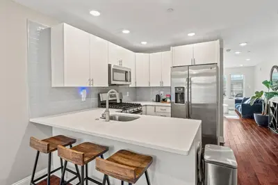 a kitchen with white cabinets and a sink and stools at Getaway in the heart of the city in Philadelphia