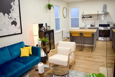 a living room with a blue couch and a kitchen at Newly Renovated 1 Bedroom Executive Apartment in Kearny