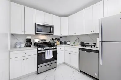 a kitchen with white cabinets and a stove and a microwave at Cozy Family Getaway - NYC & NWK with free parking in Bayonne