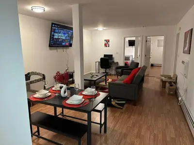 a living room with a table and a couch at Cozy Family Getaway - NYC & NWK with free parking in Bayonne