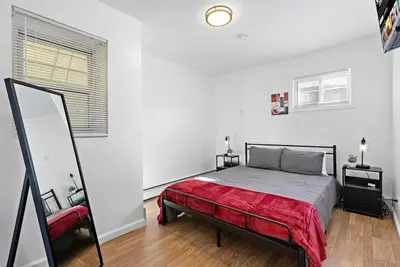 a white bedroom with a bed and a mirror at Cozy Family Getaway - NYC & NWK with free parking in Bayonne