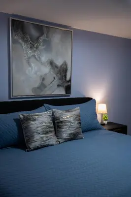 a bedroom with a blue bed with a painting on the wall at Cozy Pocono Home with a Hot Tub, Fire pit, Karaoke, Games and more! in Albrightsville