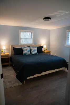 a bedroom with a large bed with two windows at Cozy Pocono Home with a Hot Tub, Fire pit, Karaoke, Games and more! in Albrightsville