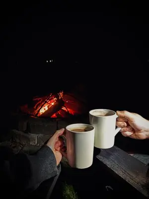 two people holding cups of coffee in front of a fireplace at Cozy Pocono Home with a Hot Tub, Fire pit, Karaoke, Games and more! in Albrightsville