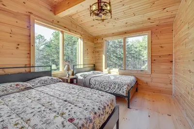 two beds in a log cabin bedroom with windows at Ski, Hike and More Spacious Log Cabin in Long Pond in Long Pond
