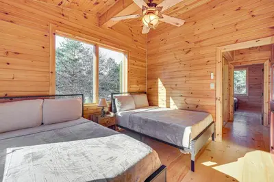 two beds in a log cabin with a ceiling fan at Ski, Hike and More Spacious Log Cabin in Long Pond in Long Pond