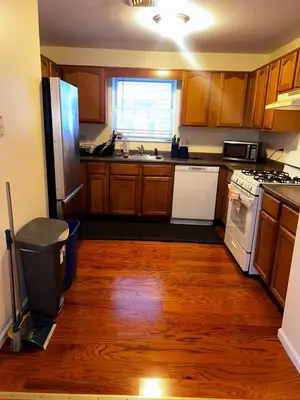 a kitchen with wooden floors and a refrigerator and a sink at 3-Bedroom Apt 5 miles AirPort in Newark