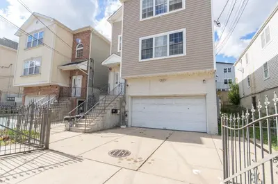 a house with a white garage door on a street at 3-Bedroom Apt 5 miles AirPort in Newark
