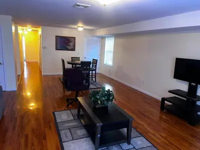 a living room with tables and chairs and a flat screen tv at 3-Bedroom Apt 5 miles AirPort in Newark